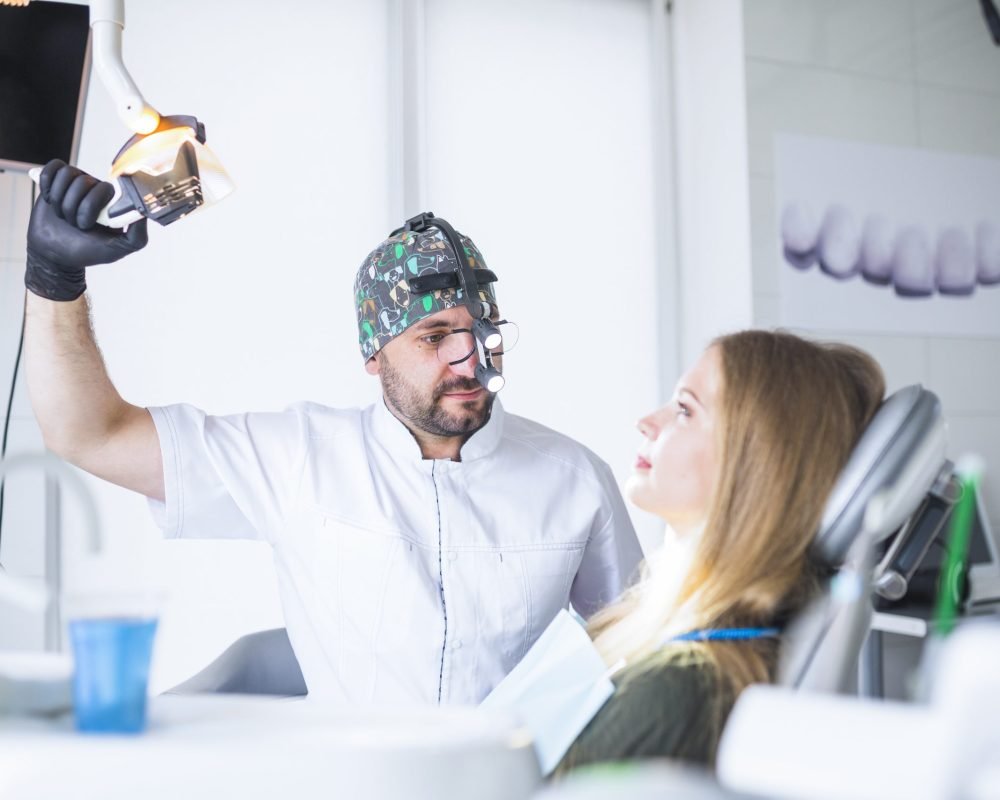 dentist-wearing-dental-loupe-binoculars-treating-female-patient dentist-wearing-dental-loupe-binoculars-treating-female-patient